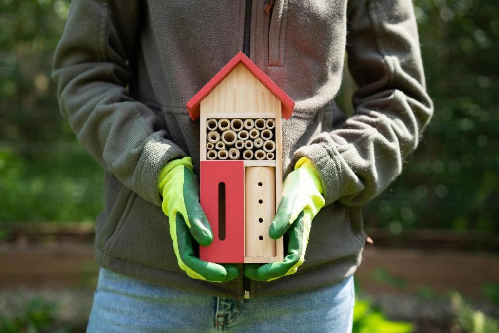 Bug hotel fatto in casa con pallet e materiali naturali, rifugio per api solitarie, coccinelle e altri insetti utili in giardino.